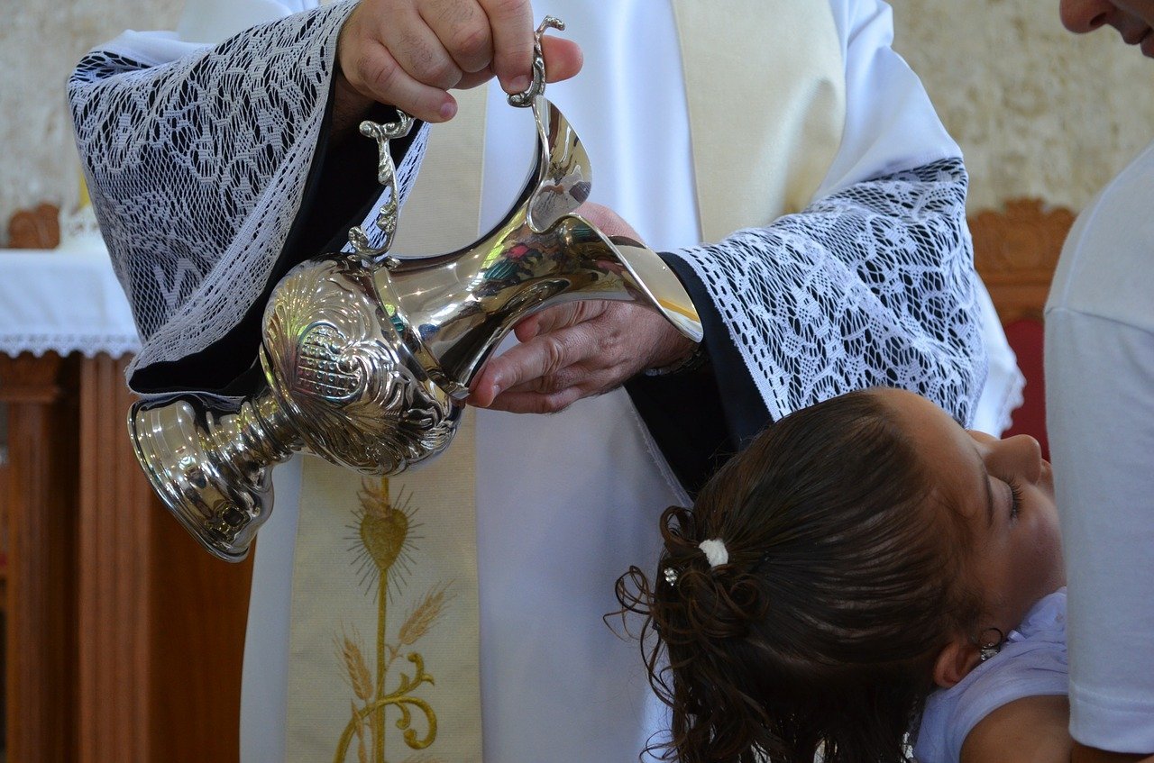 This iamge shows a young girl being baptised.