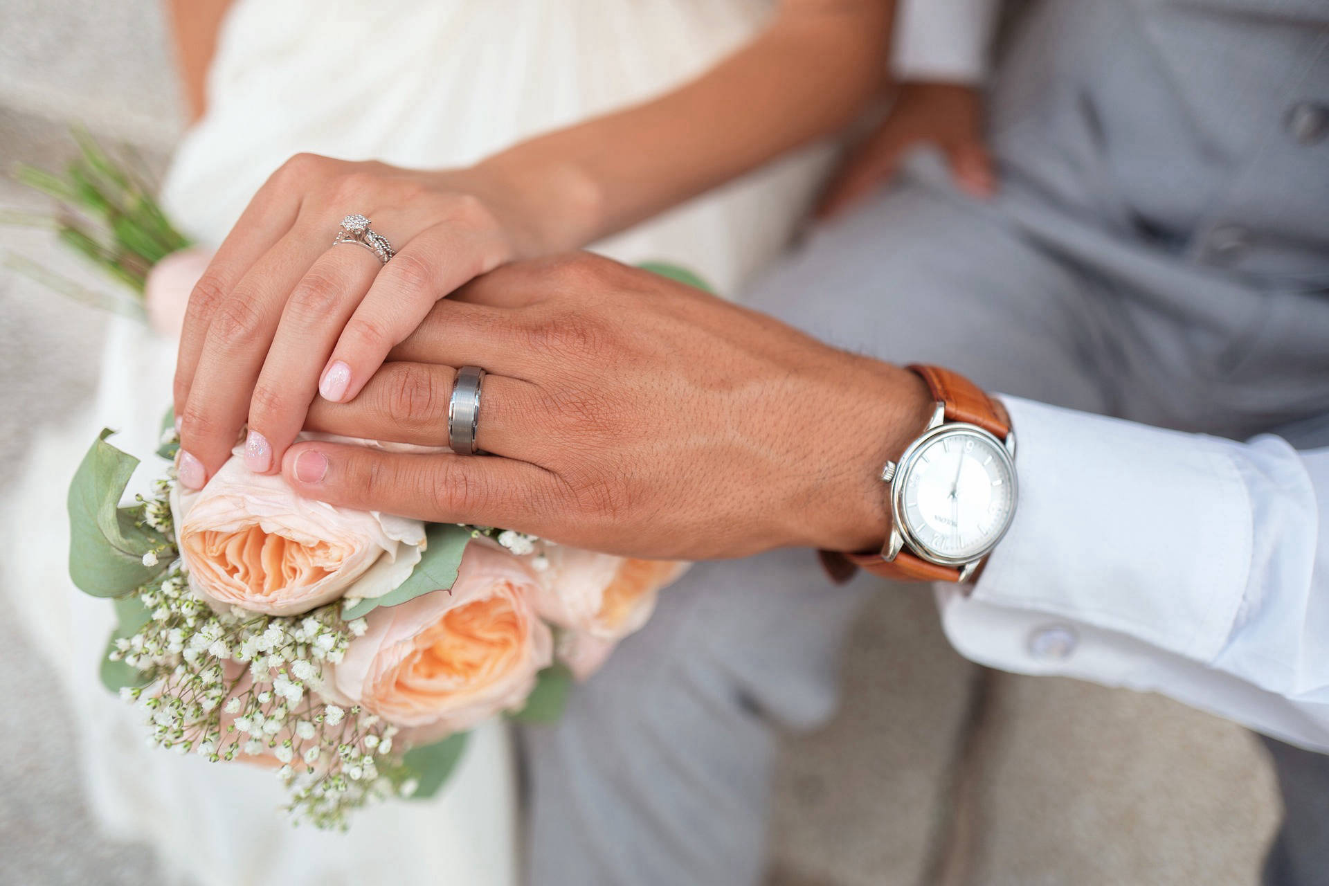 This image displays a man and woman's hand showing their wedding bands.