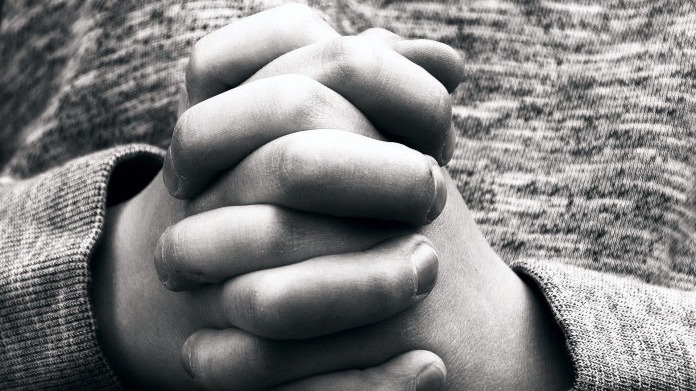 Black and white image of hand clasped in prayer